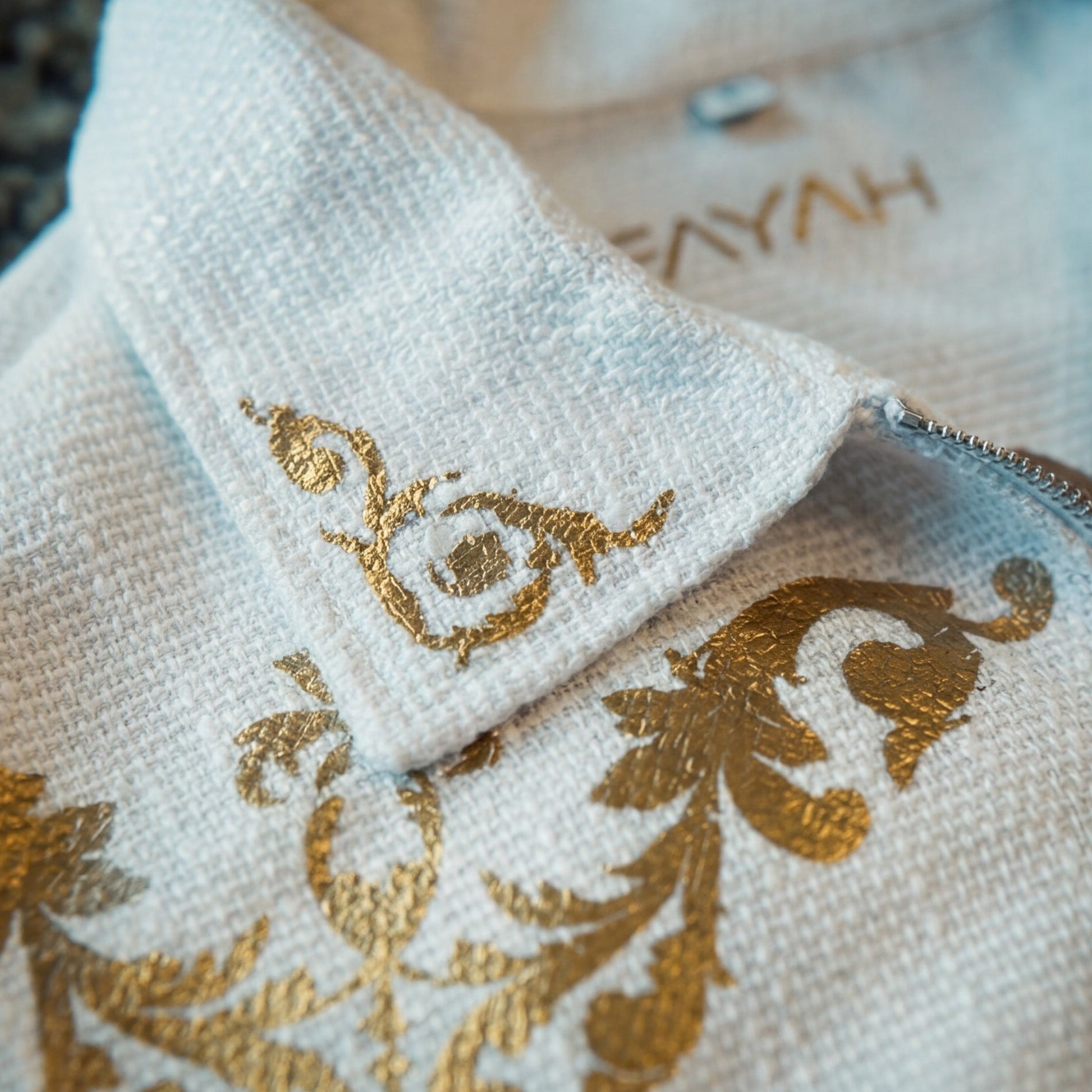 White embroidered shirts with gold designs on a marble surface and wooden background.