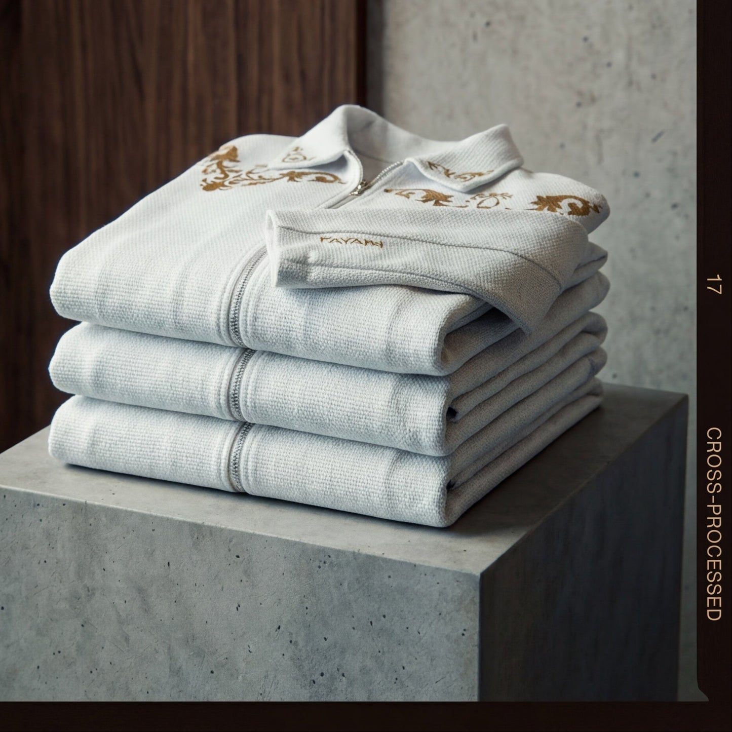 White embroidered shirts with gold designs on a marble surface and wooden background.