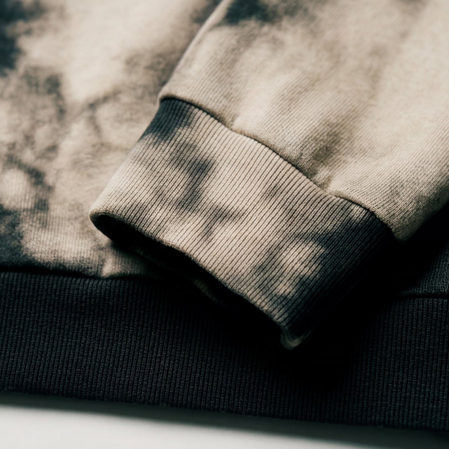 Close-up of folded sweaters in gray and black on a textured surface
